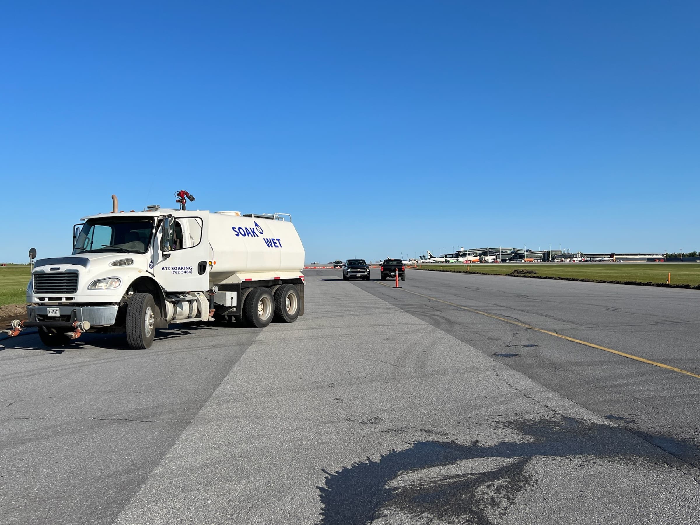 Soak N Wet truck on a runway in Ottawa, water trail visible across the tarmac